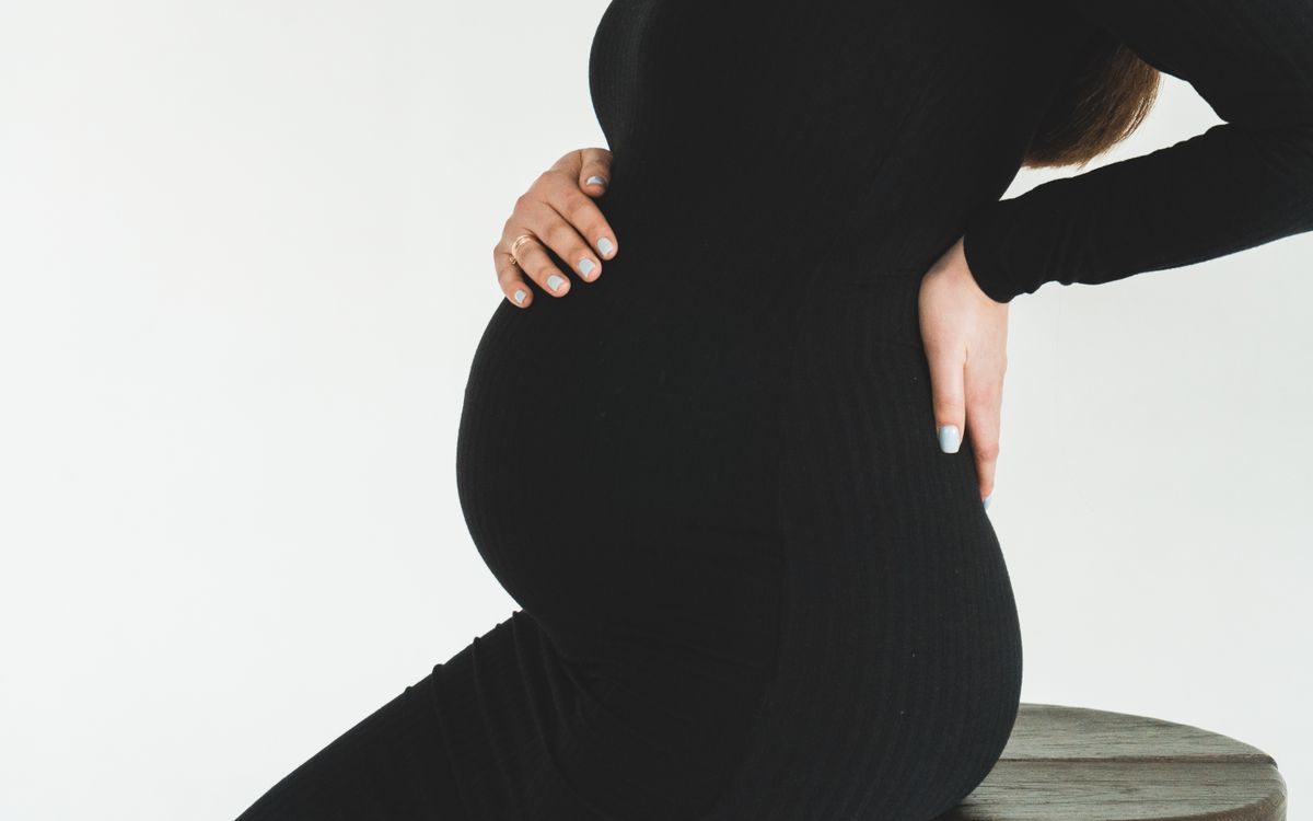 Femme enceinte tenant son bas du dos, douleur de sciatique pendant la grossesse