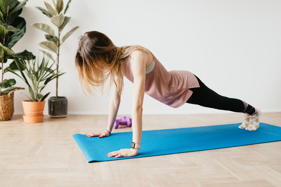 Femme réalisant un gainage en planche sur un tapis, exercice isométrique recommandé avant de reprendre la musculation avec une sciatique