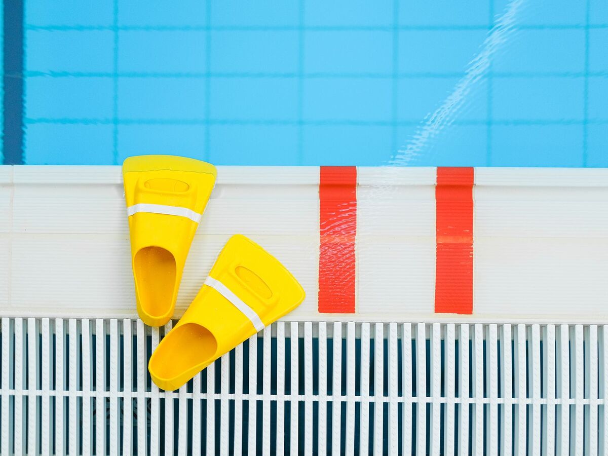 Palmes courtes de natation posées au bord d'une piscine, un accessoire utile pour nager sans forcer sur le bas du dos