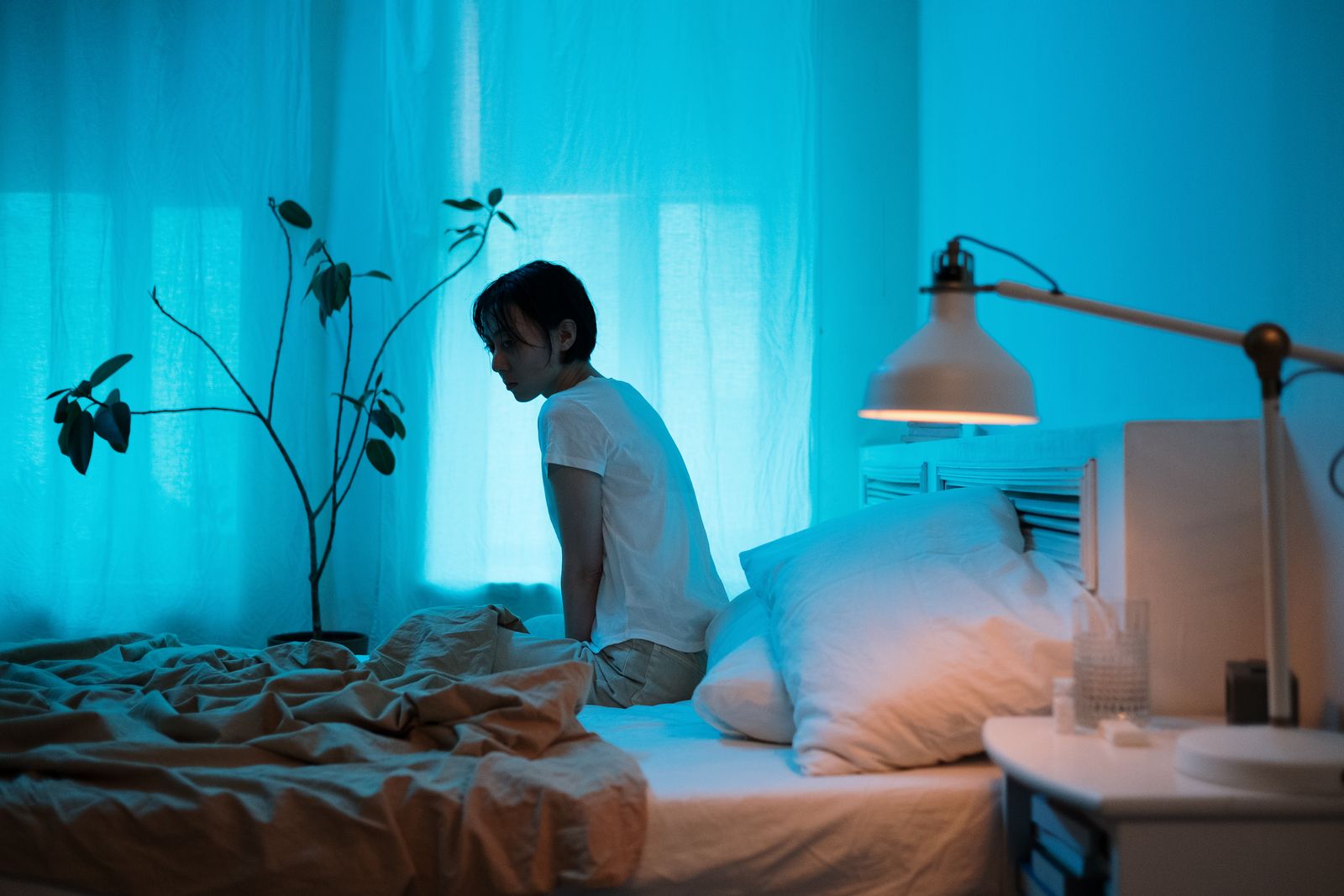 Personne qui se leve doucement du lit la nuit pour soulager une douleur de sciatique