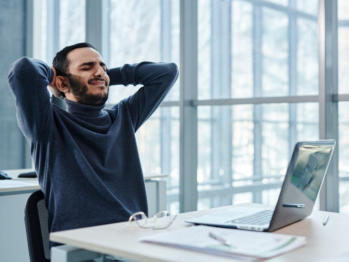 Homme assis penché en avant sur son bureau, dos rond, posture qui aggrave la sciatique en position assise