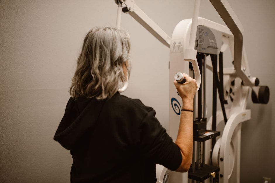 Personne d'âge mûr utilisant une machine de tirage guidée en salle de sport pour se muscler le dos sans risque en cas de sciatique