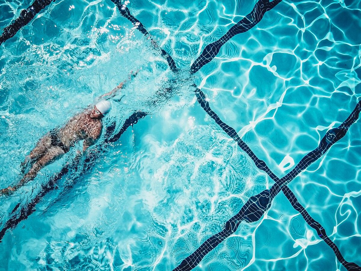 Nageur en crawl vu de dessus dans une piscine, une nage recommandée en cas de sciatique