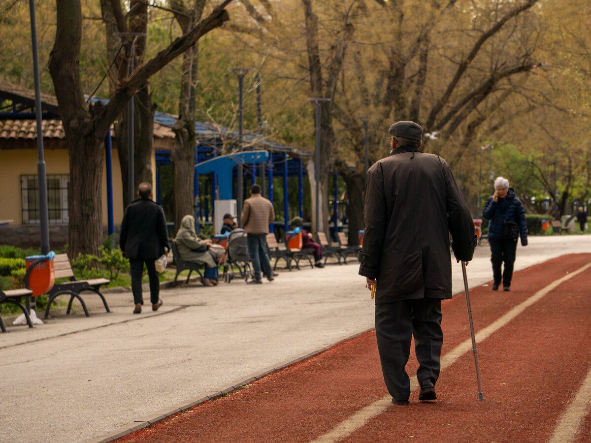 Personne âgée s'arrêtant de marcher en s'appuyant sur une canne, illustrant la claudication liée à un canal lombaire étroit