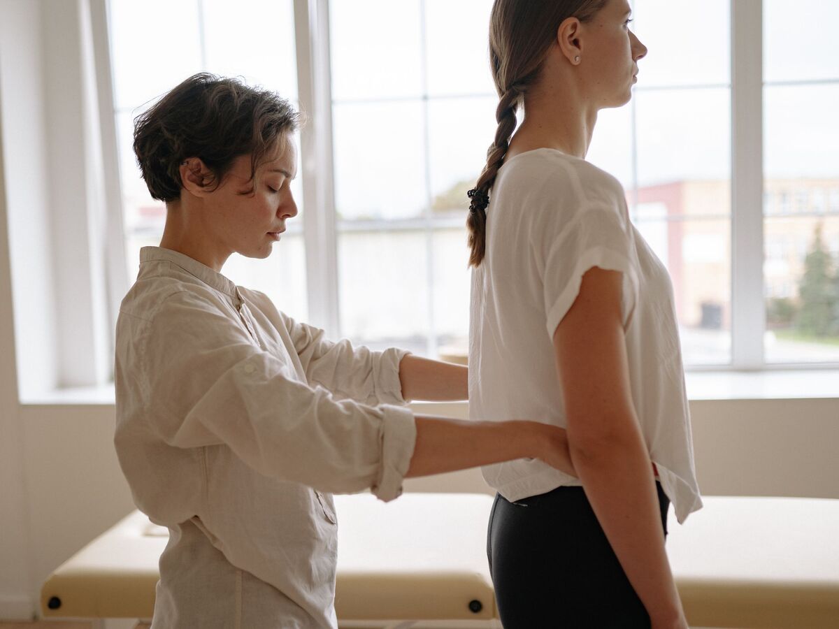 Kinésithérapeute évaluant la posture du dos d'une patiente debout