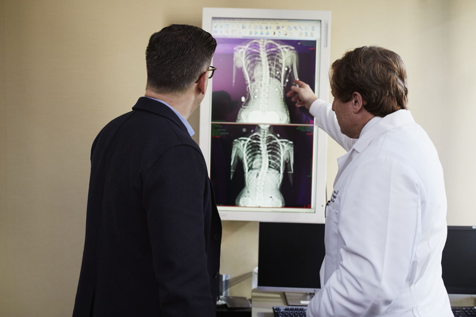 Médecin montrant à un patient des images d'imagerie médicale de la colonne vertébrale pour diagnostiquer une compression nerveuse
