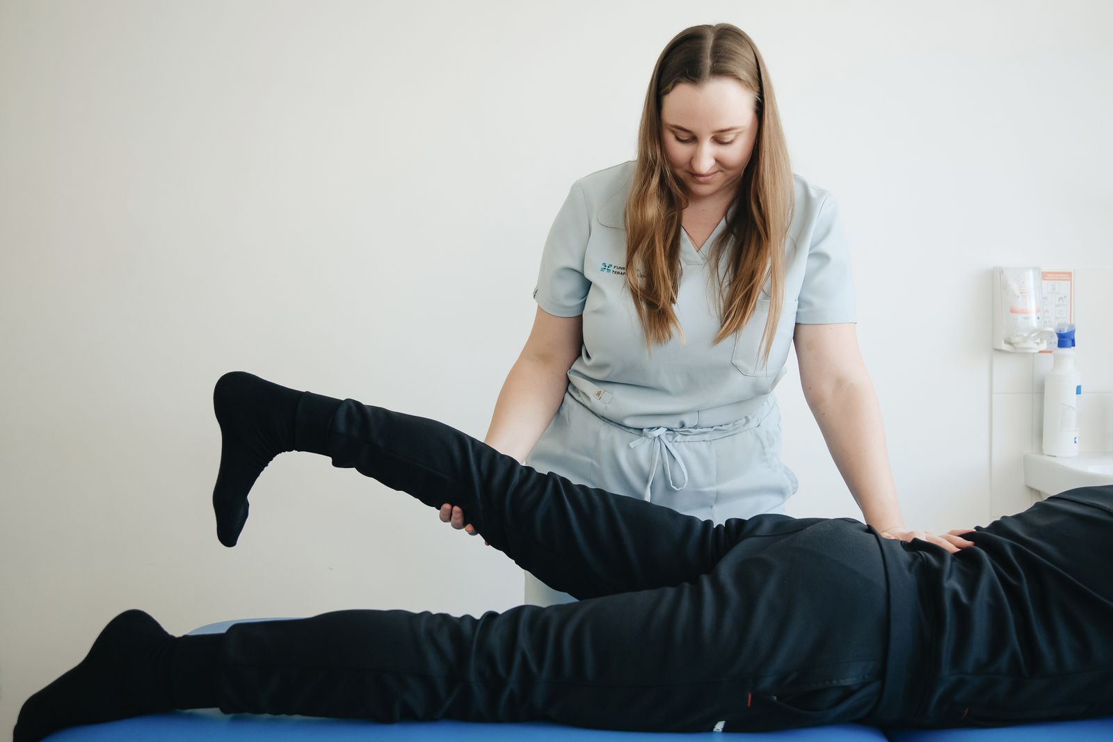 Kinésithérapeute testant la jambe d'un patient allongé pour orienter le diagnostic entre sciatique et fausse sciatique