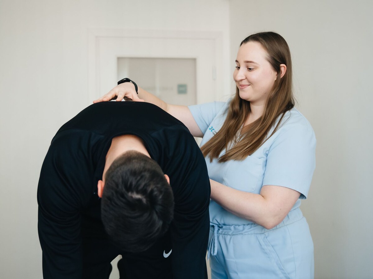 Kinésithérapeute accompagnant un patient dans un exercice de mobilisation du dos