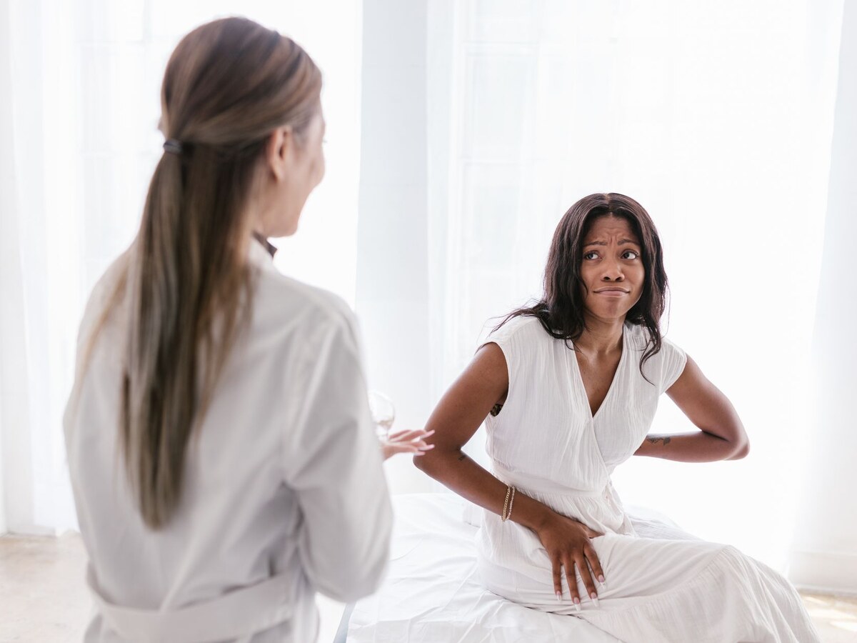 Femme souffrant d'une douleur au bas du dos lors d'une consultation avec son médecin traitant