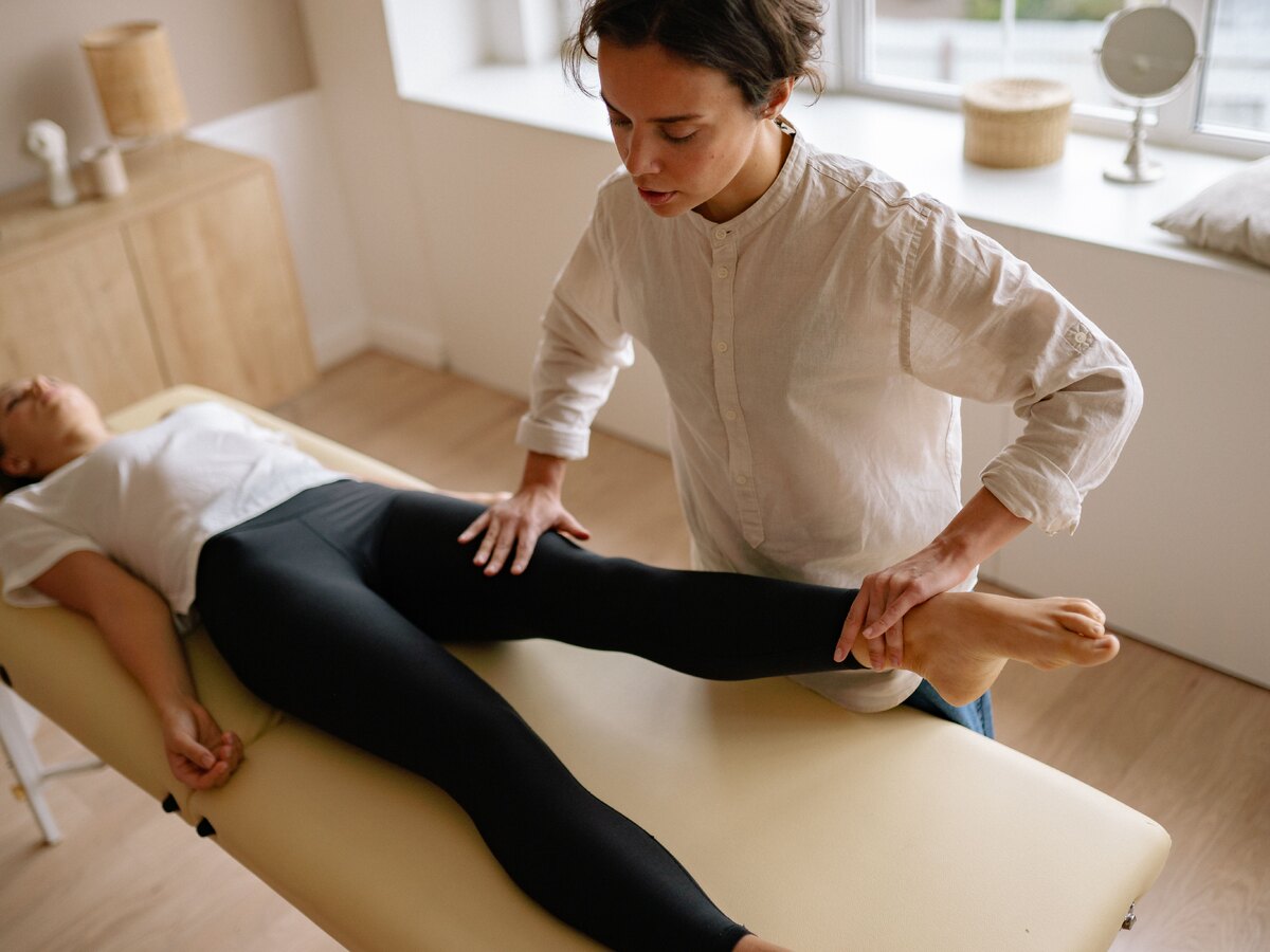 Kinésithérapeute testant la jambe d'une patiente le long du trajet du nerf sciatique
