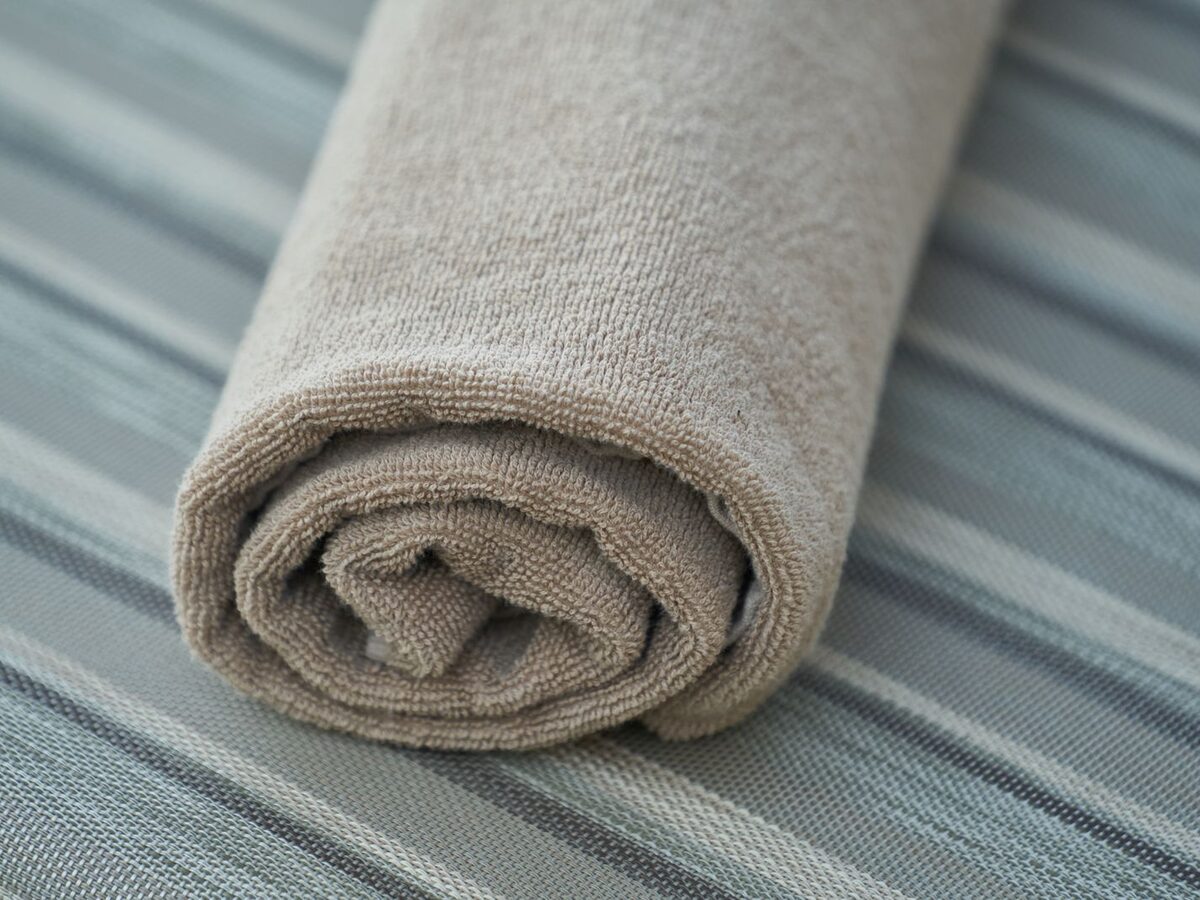 Serviette éponge roulée serré, utilisable comme rouleau lombaire improvisé pour tester un soutien du bas du dos